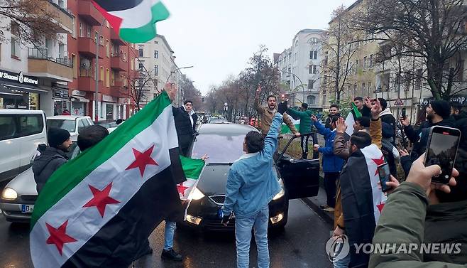 독일에서 아사드 정권 몰락 축하하는 시리아인들 (베를린 AFP=연합뉴스) 8일(현지시간) 독일 베를린에서 시리아 교민들이 아사드 정권 몰락에 기뻐하는 시위를 열고 있다. 2024.12.08
