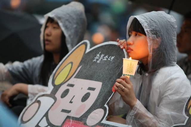 ▲ 2008년 6월 18일 오후 서울 시청앞 광장에서 열린 미국산 쇠고기 수입반대 촛불문화제에서 한 시민이 촛불소녀 피켓을 들고 앉아 있다.ⓒ연합뉴스