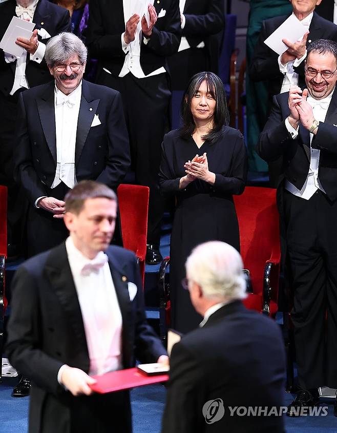 노벨화학상 수상자에 박수 보내는 한강 (스톡홀름=연합뉴스) 김도훈 기자 = 2024 노벨문학상 수상자인 한강 작가가 10일(현지시간) 스웨덴 스톡홀름 콘서트홀에서 열린 시상식에서 노벨 화학상을 받은 AI 기업 딥마인드 연구원 존 점퍼에게 박수를 보내고 있다. 2024.12.11 superdoo82@yna.co.kr