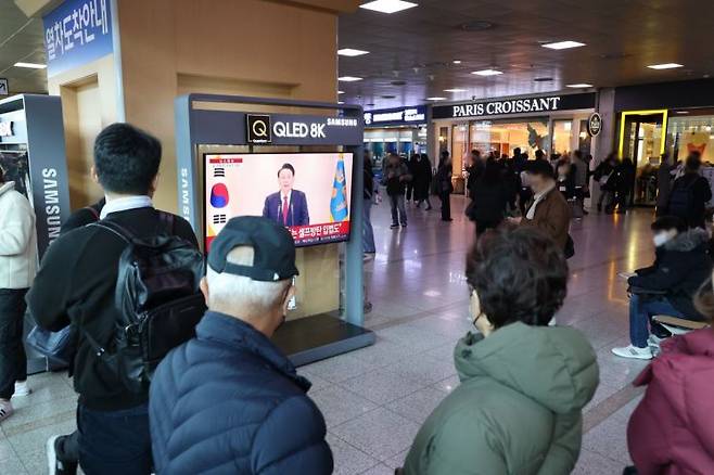 12일 오전 서울역에서 시민들이 윤석열 대통령 담화를 TV로 보고 있다. 연합뉴스