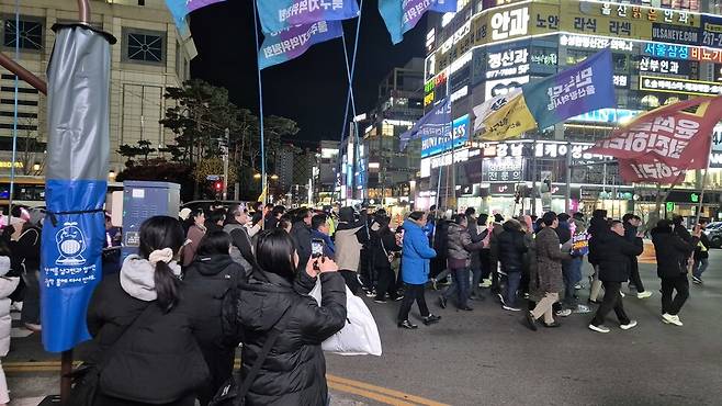 13일 저녁 윤석열 정권 퇴진 집회 참가자들이 울산 남구 삼산동 롯데백화점 앞에서 국민의힘 김기현 의원 지역사무실까지 행진을 하고 있는 가운데 행진 행렬을 본 시민들이 사진과 영상을 촬영하며 응원하고 있다. 주성미 기자