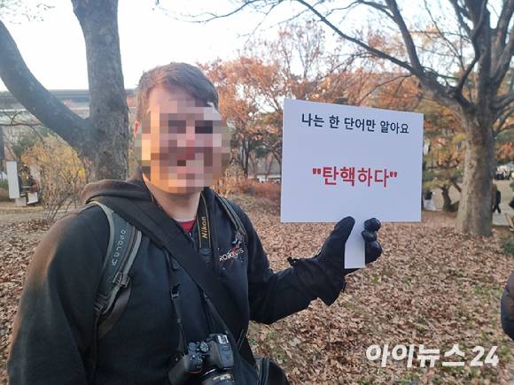 14일 서울 여의도공원에서 윤석열 대통령 탄핵집회에 참석한 30대 미국인 남성 조나단이 탄핵을 지지하는 내용의 피켓을 들고 사진을 찍고 있다. [사진=박정민 기자]