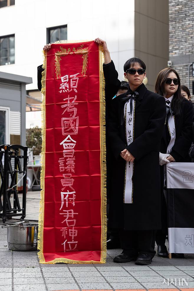 퍼포먼스 참가자가 ‘현고국회의원부군신위’라고 쓰인 명정(죽은 사람의 관직 등을 적은 기)을 들고 있다.ⓒ김흥구