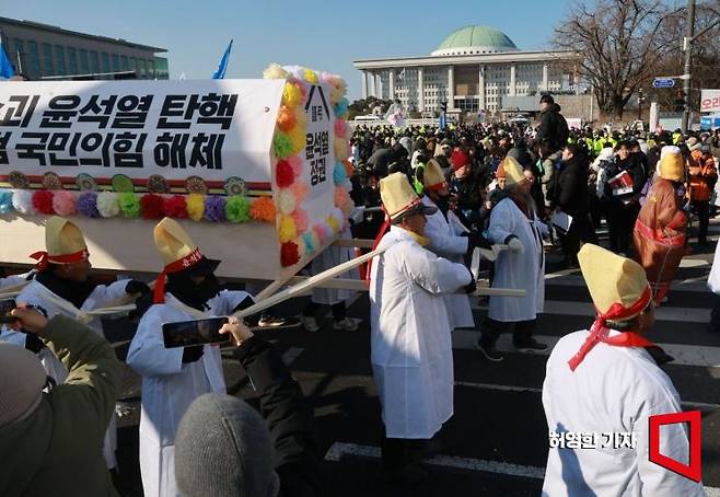 윤석열 대통령에 대한 2차 탄핵 표결을 앞둔 14일 서울 여의도 국회 앞에서 열린 탄핵 촉구 집회에서 전국농민회 참가자들이 상여 모양 조형물을 메고 국회 앞을 지나고 있다. 허영한 기자