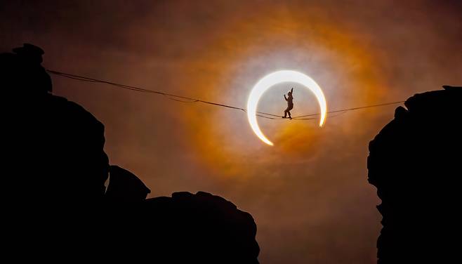 고공 외줄타기를 하는 사람 뒤로 달이 지구와 태양 사이를 통과하는 금환일식이 진행되고 있다. / 2024 Nature’s Best Photography
