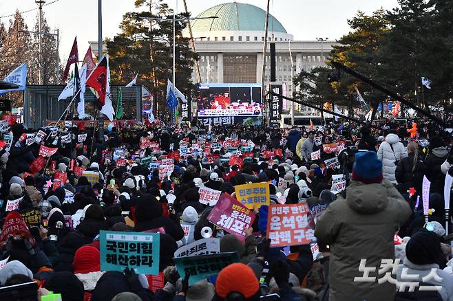 14일 오후 서울 여의도 국회의사당 앞에서 시민들이 윤석열 대통령 탄핵소추안 재표결 상황을 생중계로 지켜보며 구호를 외치고 있다. 류영주 기자