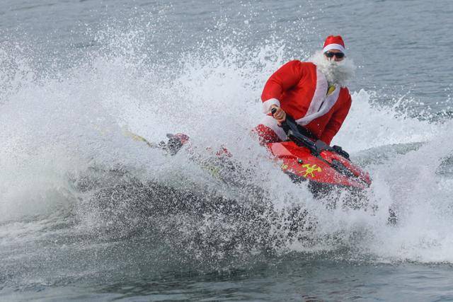 브라질 리우데자네이루의 코파카바나 해변에서 17일 산타클로스 옷을 입은 한 남성이 어린이들에게 선물을 나눠주기 위해 제트스키를 타고 파도를 가르며 달리고 있다. 리우데자네이루=EPA 연합뉴스