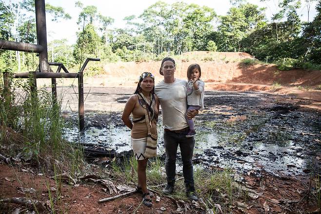 와오라니족 지도자 네몬테 넨키모와 ‘아마존 프론트라인즈’ 설립자 미치 앤더슨이 자신들의 딸 다이메와 함께 에콰도르 북부 도시 라고 아그리오 근처의 유독성 원유 폐기물 웅덩이 옆에서 사진을 찍고 있다. ‘아마존 프론트라인즈’ 제공