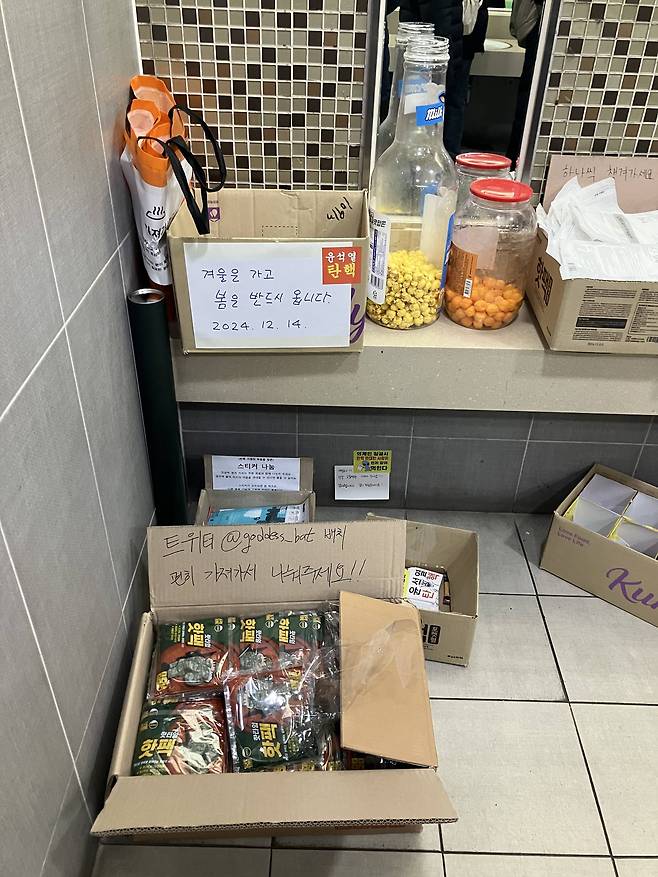 Free items, comprised of disposable hand warmers, face masks, snacks and light sticks arranged in a corner of the National Assembly Station's bathroom on Dec. 14 [SCREEN CAPTURE]