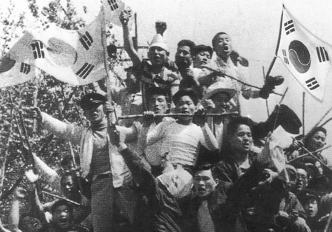 A photo from the April Revolution in 1960 showing young protesters chanting while using the Korean flag, or Taegeukgi. [JOONGANG DB]