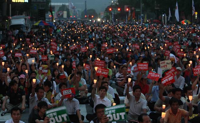 Protesters in central Seoul hold candles and placards demanding the ban on U.S. beef imports during the former Lee Myung-bak administration on June 26, 2008. [JOONGANG ILBO]