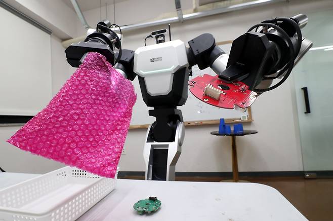 로봇 회사 레인보우로보틱스의 이동형 양팔 로봇 ‘RB-Y1’이 양쪽 집게를 이용해 부품을 비닐에 넣는 모습. 보통의 외팔 로봇보다 관절을 한 개씩 더 지녀 사람과 비슷하게 팔을 움직일 수 있고 몸통도 아래위 50㎝ 넘게 움직일 수 있다. /대전=신현종 기자