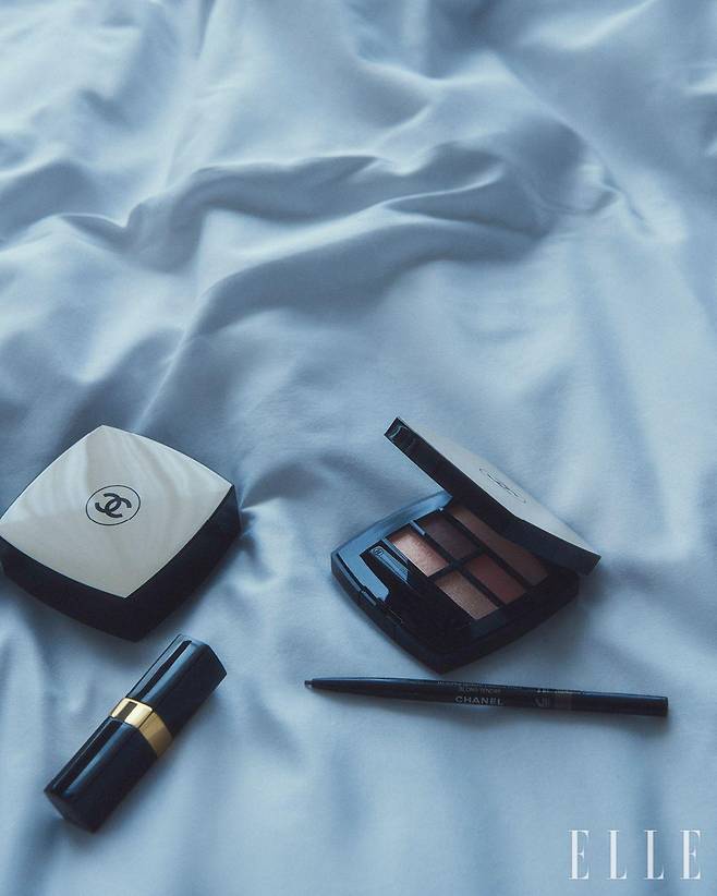 행사장에 참석하기 위해 메이크업을 받고 있는 민지와 룩을 완성해 준 샤넬의 뷰티 제품들. 레 베쥬 쿠션, 레 베쥬 아이섀도우 팔레트, 스틸로 쑤르씰 오뜨 프레시지옹 그리고 루쥬 코코 플래쉬.