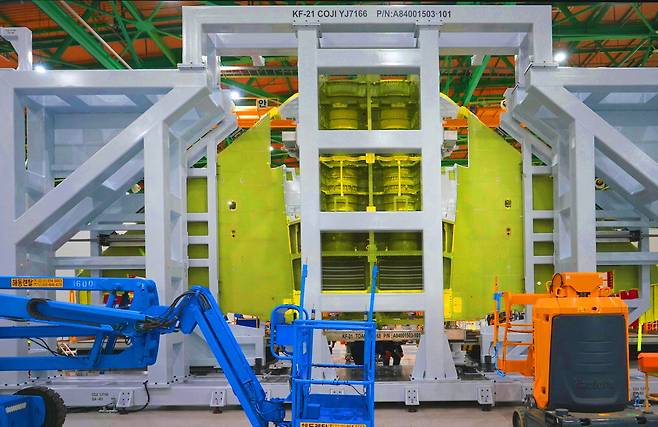경남 사천 한국항공우주산업(KAI)에서 조립 중인 한국형 전투기 KF-21의 양산 1호기가 지난 12일 중앙 동체와 주 날개 결합 상태로 세워져 구멍 뚫기 작업이 진행되고 있다. 시험평가용 기체가 아닌 공군 납품용 양산 1호기 기체가 언론에 공개된 것은 처음이다(아래 작은 사진). 이 작업 이후에는 전방·중앙·후방 동체가 결합돼 전투기 형상을 갖춘 뒤 엔진과 각종 항공전자장비가 탑재돼 완성된다. 큰 사진은 시험평가용 기체를 조립한 것으로 독자 이해를 위해 함께 게재했다.  KAI