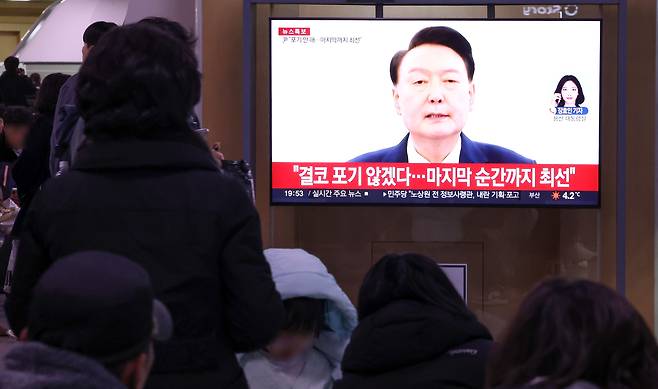 윤석열 대통령의 탄핵소추안이 국회에서 가결된 14일 오후 서울역에서 시민들이 윤석열 대통령의 대국민 담화를 TV를 통해 지켜보고 있다. [연합]