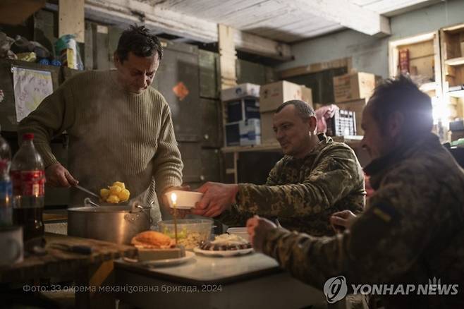 24일(현지시간) 우크라이나 드니프로페트로우스크 지역 인근 전선에 주둔 중인 우크라이나 군인들이 크리스마스 이브를 맞아 저녁 식사를 하고 있다. <사진=EPA 연합뉴스>