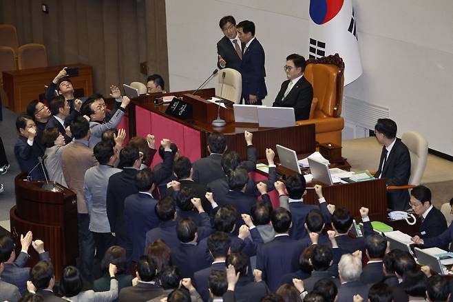 우원식 국회의장이 27일 국회 본회의에서 한덕수 대통령 권한대행에 대한 탄핵소추안 의결 정족수가 151명이라고 밝히자 국민의힘 의원들이 의장석으로 몰려가 항의하고 있다. /뉴스1