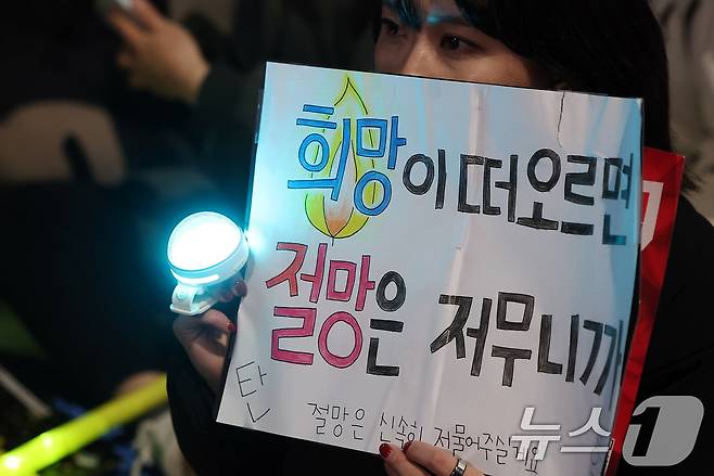 윤석열 대통령에 대한 국회의 2차 탄핵소추안 표결을 하루 앞둔 13일 오후 서울 영등포구 여의도 국회 앞에서 열린 '윤석열 즉각 탄핵 구속 촉구 촛불문화제'에서 참가자가 응원봉과 손피켓을 들어 보이고 있다. 2024.12.13/뉴스1 ⓒ News1 김진환 기자