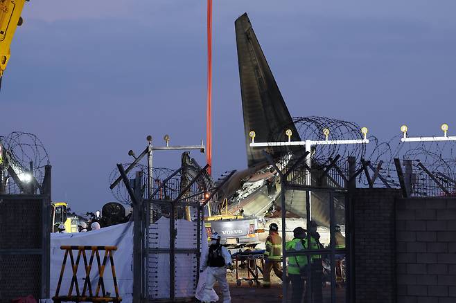 29일 오후 전남 무안군 무안국제공항에서 발생한 제주항공 여객기 충돌 폭발 사고 현장에서 대형 크레인이 파손된 기체 후미를 들어 올리고 있다. /연합뉴스