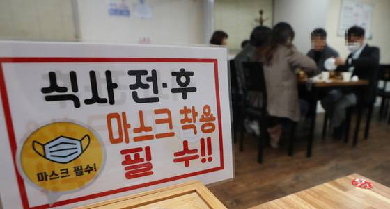 A sign at a restaurant in Ulsan asks customers to wear a mask before and after eating on Oct. 18, 2021, when Covid-19 regulations such as shortened store operating hours and rules restricting gatherings to less than 10 people took place. [YONHAP]