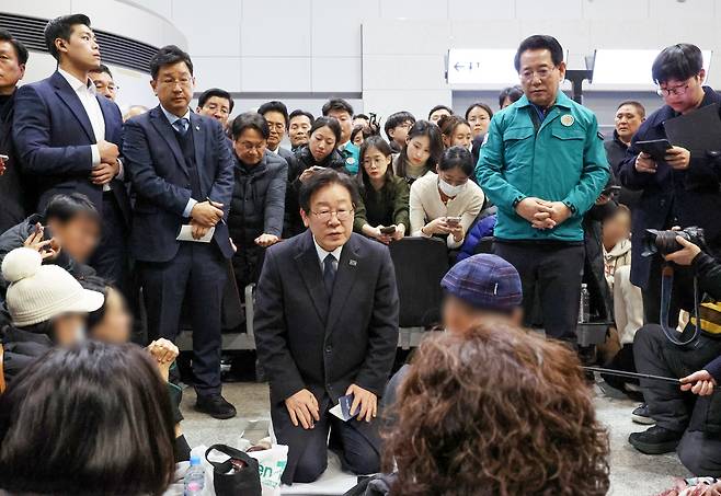 더불어민주당 이재명 대표가 29일 오후 전남 무안국제공항에서 무릎을 꿇은 채 제주항공 여객기 폭발사고 탑승객 가족들을 위로하고 있다. [연합]