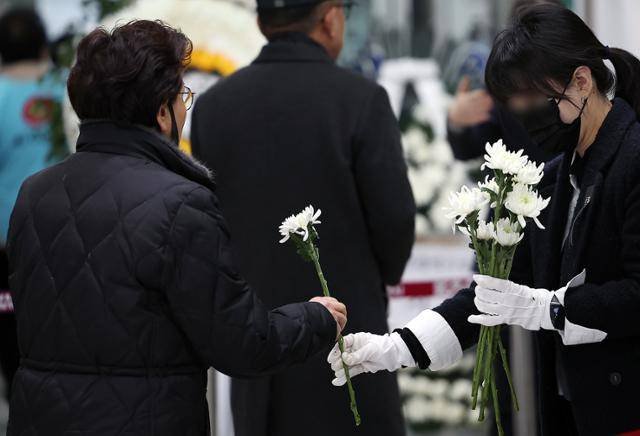 3일 전남 무안군 무안국제공항에 마련된 제주항공 여객기 참사 희생자 합동분향소에서 한 자원봉사자가 조문객에게 국화를 나눠주고 있다. 뉴스1