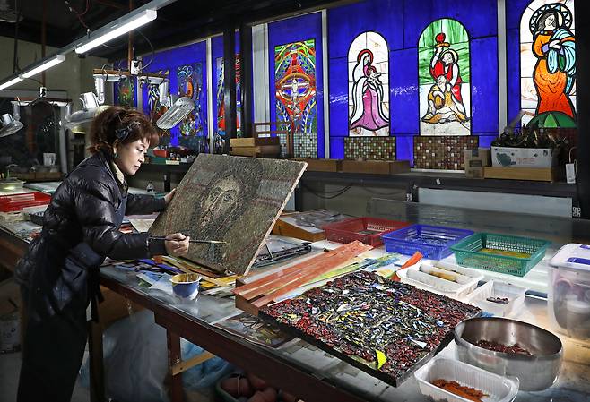 Stained glass artist Choi Wook-mi, the head of Piniel Sculpture Art Research Institute, adds finishing touches to her work at the institute in Anseong, Gyeonggi. [PARK SANG-MOON]