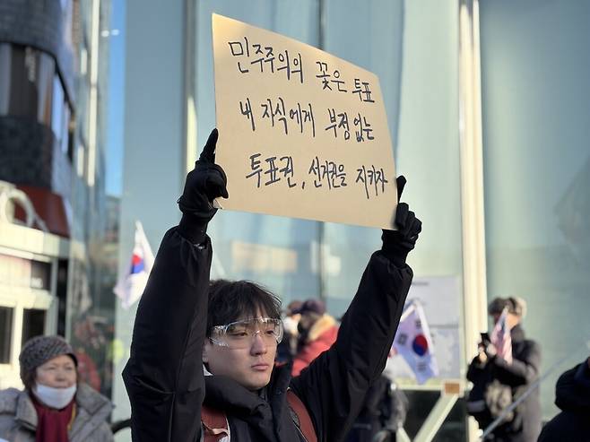 3일 오전 6시경 서울 용산구 한남동 대통령 관저 주변에서 윤지환씨(가명·32)는 '민주주의의 꽃은 투표. 부정 없는 투표권, 선거권을 지키자'라고 적힌 피켓을 머리 위로 들고 있다. ⓒ시사저널 정윤경