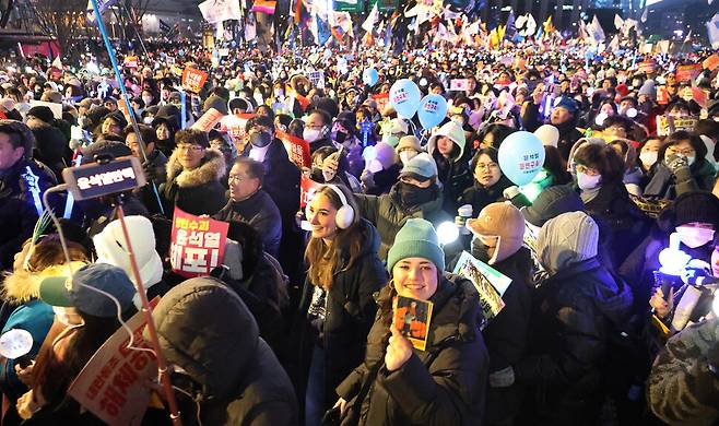 시민과 외국인들이 한데 어울려 2024년 12월28일 밤 서울 광화문 앞 사직로 거리를 행진하고 있다.