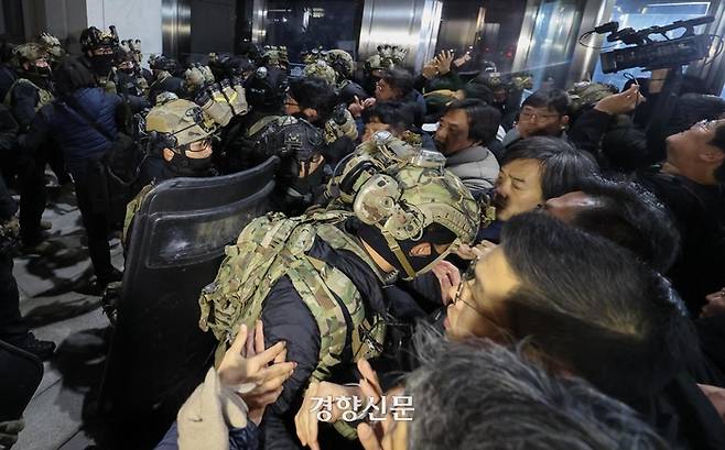 윤석열 대통령이 지난해 12·3 비상계엄을 선포한 직후 자정을 넘긴 새벽 서울 여의도 국회의사당에 도착한 무장군인들이 국회본청 진입을 시도하자 국회 직원 등이 격렬히 막아서고 있다. 성동훈 기자