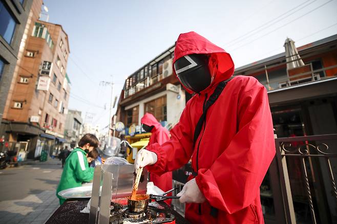 지난 2021년 10월 31일 오후 서울 용산구 이태원 거리에서 오징어게임 분장을 한 상인들이 달고나를 만들어 팔고 있다. [뉴시스]