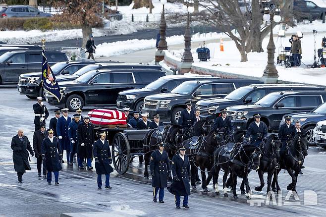 [워싱턴=AP/뉴시스] 지미 카터 전 미국 대통령의 운구 행렬이 7일(현지시각) 미국 워싱턴D.C. 국회의사당으로 향하고 있다. 카터 전 대통령의 운구는 이날 오전 조지아주 애틀란타 카터센터를 출발해 미 의회 중앙홀에 일시 안치돼 연방 상·하원 의원들이 참석한 가운데 추도식이 거행됐다. 오는 9일 워싱턴 국립대성당에서 국가 장례식이 치러진다. 2025.01.08.
