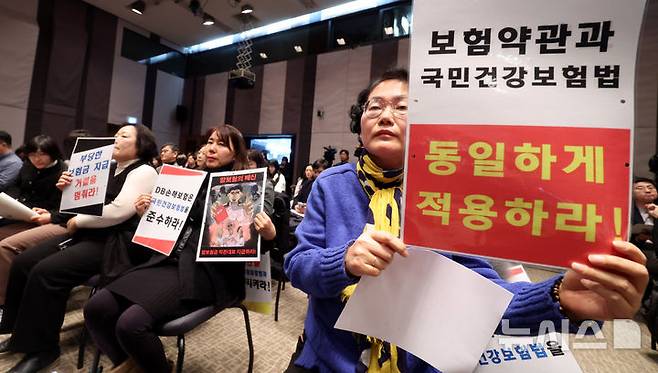 [서울=뉴시스] 추상철 기자 = 9일 오후 서울 중구 프레스센터에서 열린 '의료체계 정상화를 위한 비급여 관리 및 실손보험 개혁방안 정책토론회'에서 보험이용자협회 활동가들이 '보험약관과 국민건강보험법 동일 적용' 등을 촉구하는 피켓을 들고 있다. 2025.01.09. scchoo@newsis.com