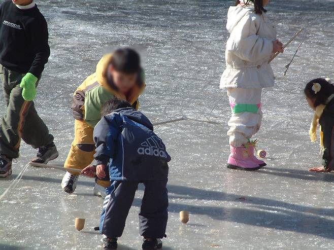 In this undated photo, children play paengi chigi (top spinning) on ice. [JOONGANG ILBO]