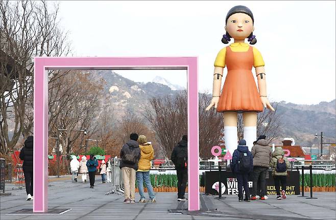 서울 종로구 광화문광장에 설치된 넷플릭스 드라마 오징어게임2에 등장하는 ‘영희’ 조형물 앞에서 시민들이 기념촬영을 하고 있다. (연합뉴스)