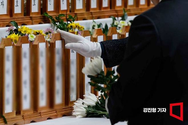 제주항공 여객기 참사로 179명의 사망자가 발생한 가운데 30일 전남 무안국제공항 인근 무안스포츠파크에 희생자 애도를 위해 마련된 합동분향소를 찾은 조문객이 희생자 위패를 만지고 있다. 강진형 기자