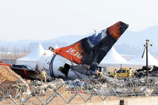 제주항공 여객기 참사 16일째인 13일 오전 무안국제공항 사고 현장에서 소방 대원들이 기체에 덮인 방수포를 걷어내고 있다. [연합뉴스]