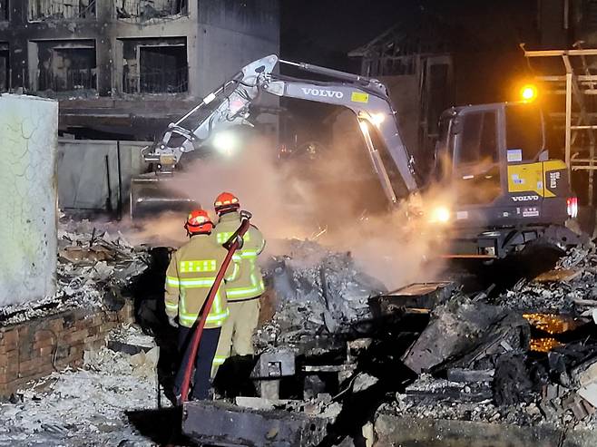 소방대원들이 중장비를 투입해 잔해물을 걷어내며 화재 진화작업을 하고 있다. [연합]