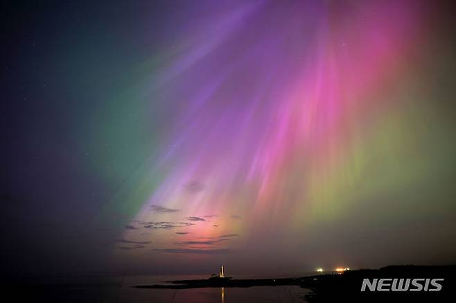 [휘틀리 베이=AP/뉴시스] 10일(현지시각) 영국 노스이스트 코스트의 휘틀리 베이에 있는 세인트 메리 등대 상공에 북극광(오로라)이 빛나고 있다. 2024.05.11.