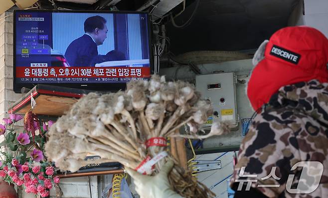 고위공직자범죄수사처와 경찰로 구성된 공조수사본부가 윤석열 대통령에 대한 2차 체포영장 집행한 15일 오후 서울 시내 전통시장에서 한 상인이 윤석열 대통령 체포 관련 뉴스를 시청하고 있다. 2025.1.15/뉴스1 ⓒ News1 임세영 기자
