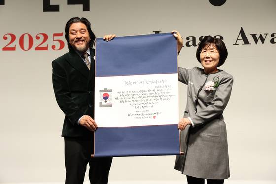Chef Edward Lee, left, receives an award from President of Corea Image Communication Institute Choi Jung Hwa, at the Korea Image Awards on Wednesday at Grand InterContinental Seoul Parnas in Gangnam District, southern Seoul. [COREA IMAGE COMMUNICATION INSTITUTE]