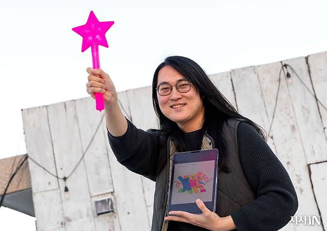 2024년 12월31일 단편선씨가 <시사IN>과 인터뷰 도중 응원봉을 들고 포즈를 취했다. 모니터 화면에 띄워진 그림은 <새노래> 프로젝트 앨범 커버. ⓒ시사IN 신선영