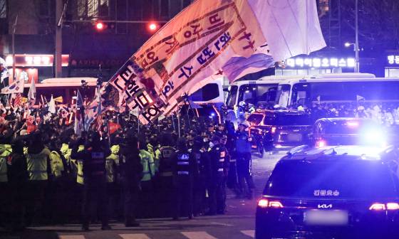 18일 오후 서울 마포구 서울서부지법 인근을 지나는 윤석열 대통령 호송 차량에 지지자들이 응원을 보내고 있다. 임현동 기자