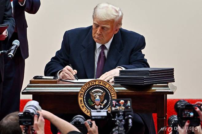 (워싱턴 AFP=뉴스1) 우동명 기자 = 도널드 트럼프 미국 대통령이 20일(현지시간) 워싱턴 '캐피털원 아레나'에서 열린 제47대 대통령 취임 축하 퍼레이드에 참석해 지지자들 앞에서 파리 기후변화 협정 재탈퇴를 비롯한 행정명령에 서명을 하고 있다. 2025.01.21 ⓒ AFP=뉴스1 Copyright (C) 뉴스1. All rights reserved. 무단 전재 및 재배포, AI학습 이용 금지. /사진=(워싱턴 AFP=뉴스1) 우동명 기자