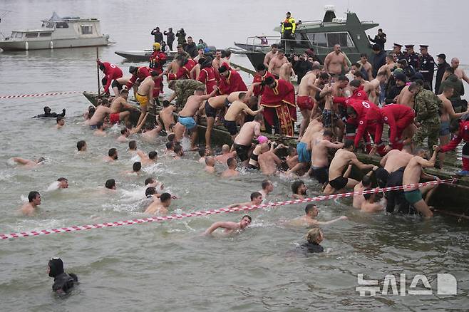 [베오그라드=AP/뉴시스] 19일(현지 시간) 세르비아 베오그라드에서 주현절 기념행사가 열려 붉은 옷을 입은 정교회 사제들이 십자가를 찾기 위해 다뉴브강에 뛰어들었던 신자들이 물 밖으로 나오는 것을 돕고 있다. 이날 동방 정교회 사제가 물에 던진 나무 십자가를 찾아오는 사람뿐 아니라 이를 찾기 위해 물에 뛰어든 사람 모두가 일 년 내내 건강하게 지낼 수 있다고 믿는다. 2025.01.20.