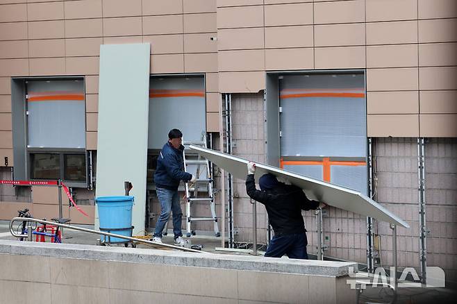 [서울=뉴시스] 이영환 기자 = 20일 오전 서울 마포구 서울서부지방법원에서 공사 관계자들이 파손된 외벽에 보수작업을 하고 있다.지난 19일 새벽 윤석열 대통령의 구속영장 발부에 지지자들이 집단 폭력 및 법원 안으로 침입하는 사고가 발생했다. 한편 서울서부지방법원은 법원은 정상적으로 운영될 것이라고 밝혔다. 다만 차량을 통한 출입은 불가능하고 출입자는 신분 확인이 필요하다고 전했다.  2025.01.20. 20hwan@newsis.com