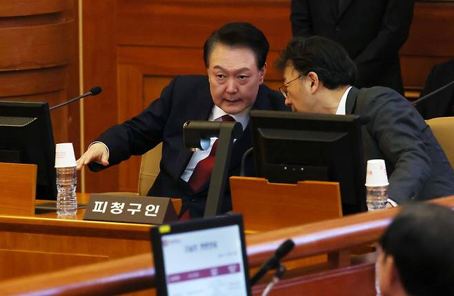 윤석열 대통령이 21일 서울 종로구 헌법재판소에서 열린 탄핵심판 3차 변론기일에 출석, 차기환 변호사와 대화를 하고 있다. /김지호 기자
