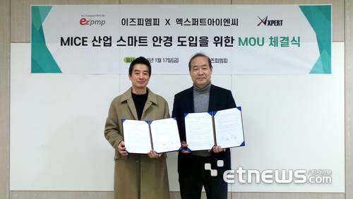 이충권 이즈피엠피 이사(왼쪽)와 정유섭 엑스퍼트아이엔씨 전무가 업무 협약서를 펼쳐보이고 있다.