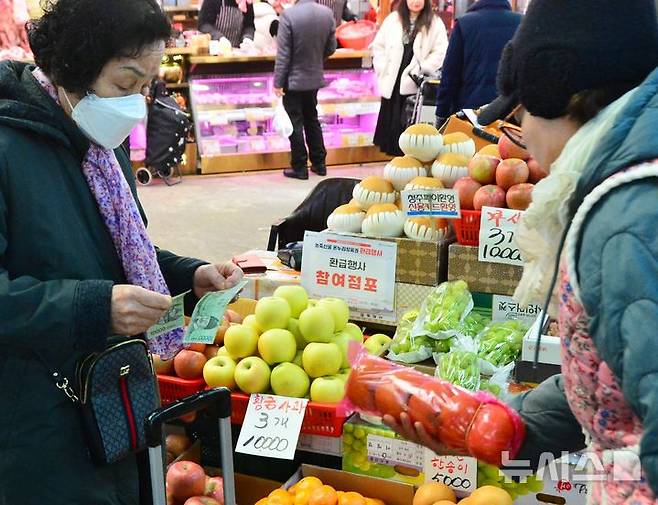 [청주=뉴시스] 서주영 기자 = 설 연휴를 앞두고 온누리상품권 환급행사가 열린 23일 충북 청주시 육거리종합시장의 행사 참여 점포에서 한 시민이 과일을 구입하고 있다. 2025.01.23. juyeong@newsis.com