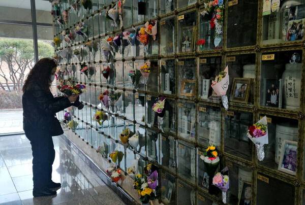 25일 인천 부평구 부평동 인천가족공원에 있는 봉안당 안에서 한 성묘객이 유골함 앞에 꽃을 걸고 있다. 박귀빈기자